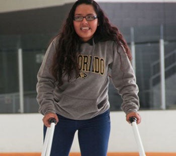 A student skates on an ice rink with the help of a skating walker.