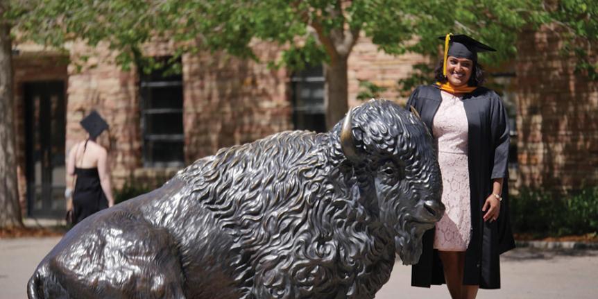 A graduate next to Ralphie sculpture